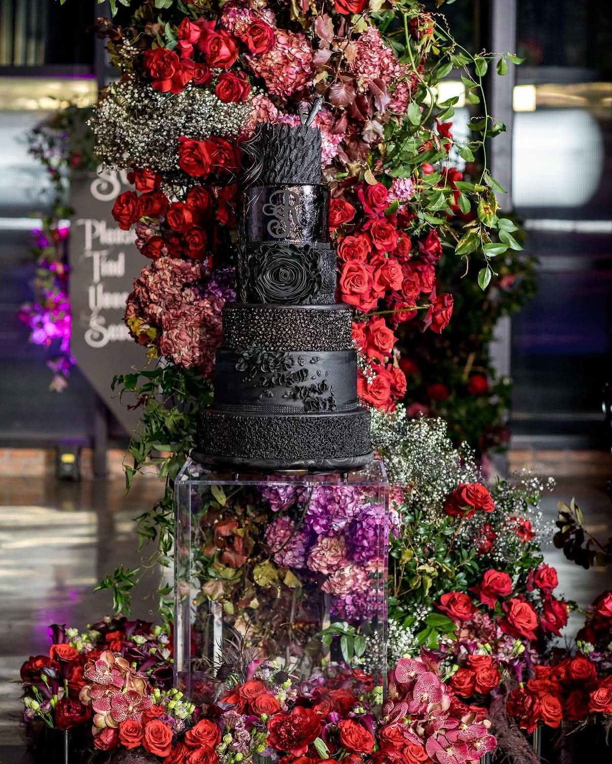 Dramatic black tiered cake with red floral installation